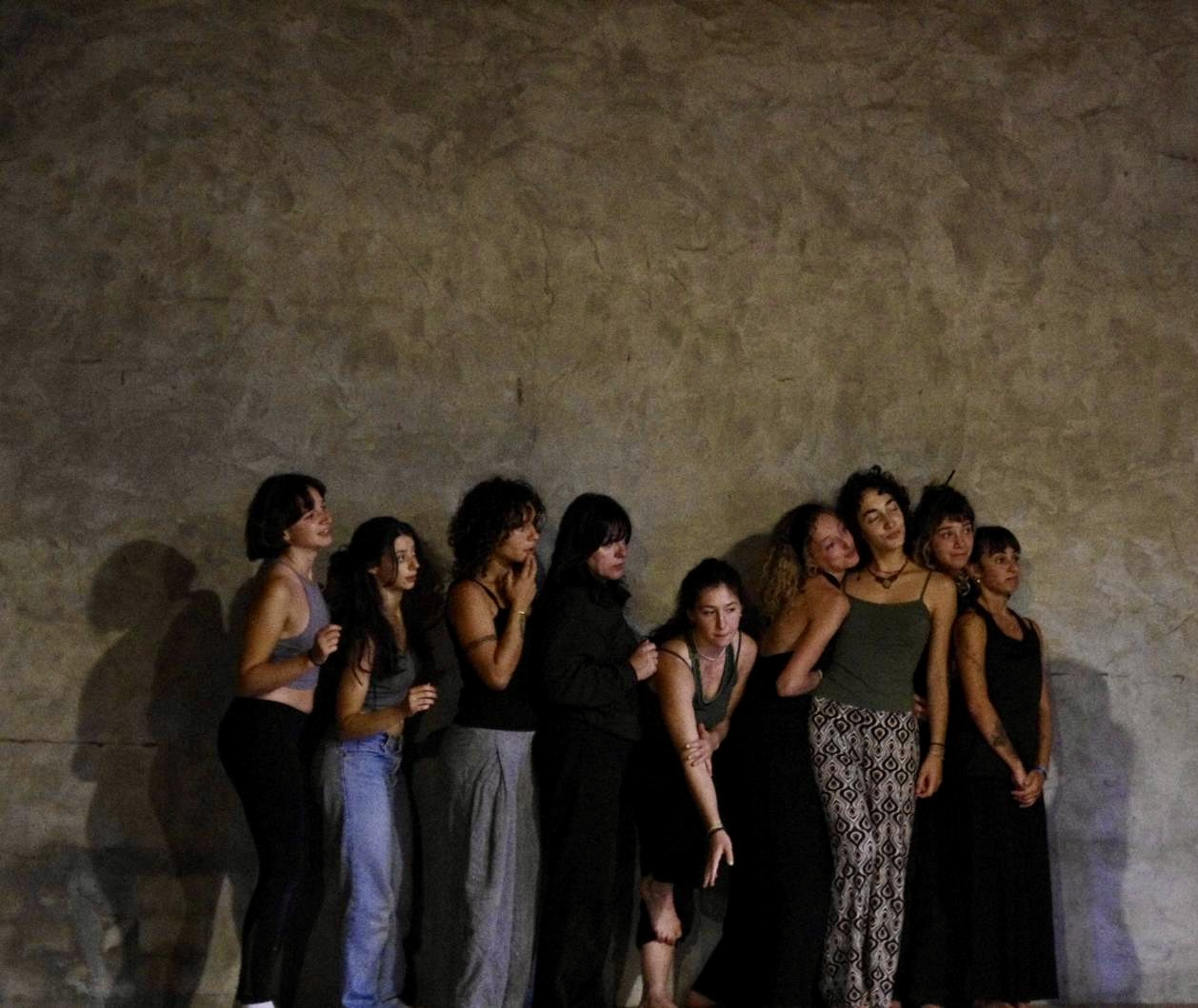 Attori adulti seduti in cerchio su un palco teatrale in penombra